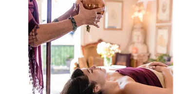 A woman receives a spiritual healing session with an energy bowl.