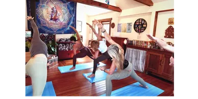Group yoga class practicing side stretches on blue mats indoors.
